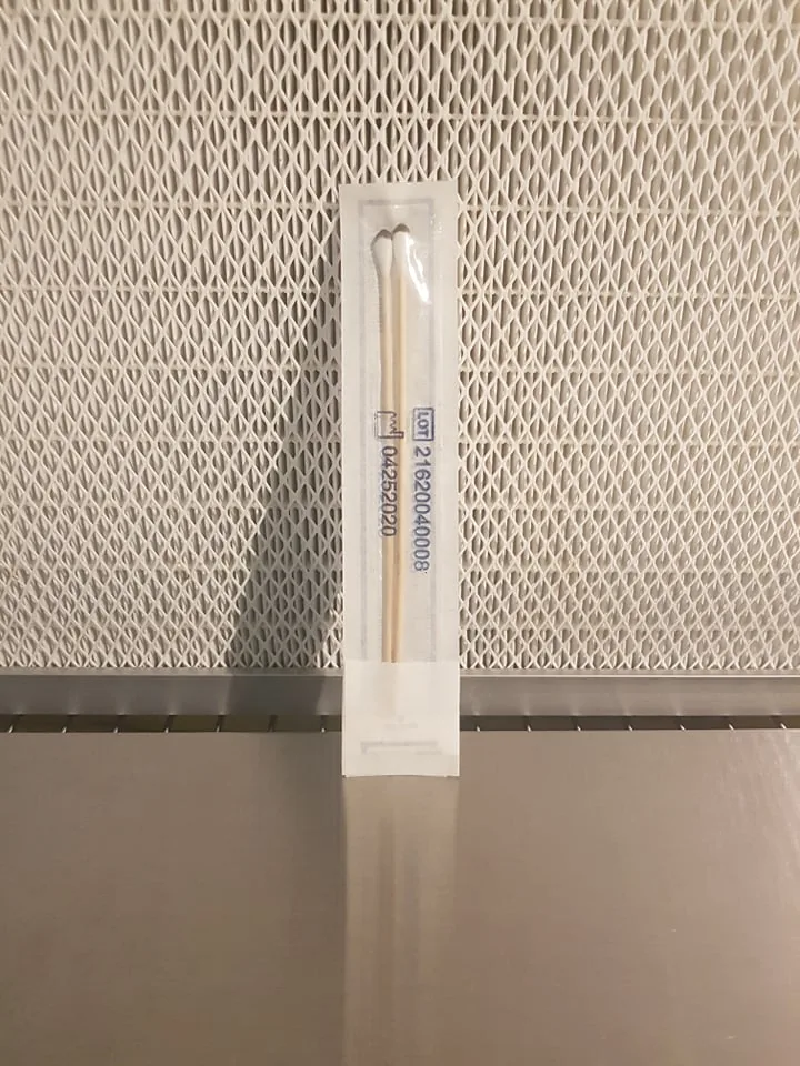 Sealed sterile spore swab in its packaging in front of a laminar flow hood filter